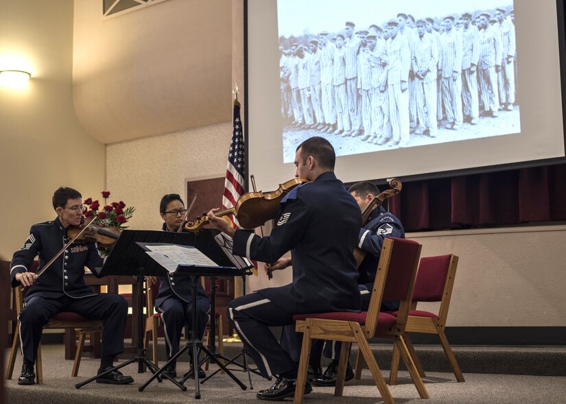 U.S. Air Force Band String members play while a slideshow of pictures are displayed during the Holocaust Commemoration at Joint Base Andrews, Md., April 26, 2017. The memorial featured an invocation, prayers and a speech made by Dr. Alfred Münzer, Holocaust survivor. (U.S. Air Force photo by Senior Airman Jordyn Fetter)
