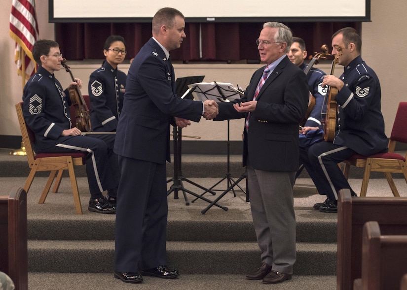 Col. Jon Julian, 11th Operations Group commander, gives a coin to Dr. Alfred Münzer, Holocaust survivor, during the Holocaust Commemoration at Joint Base Andrews, Md., April 26, 2017. Dr. Alfred Münzer was just nine months old when his family was separated during the Nazi Regime occupation of Holland, but he grew up hearing about his relatives’ hardships. (U.S. Air Force photo by Senior Airman Jordyn Fetter)
