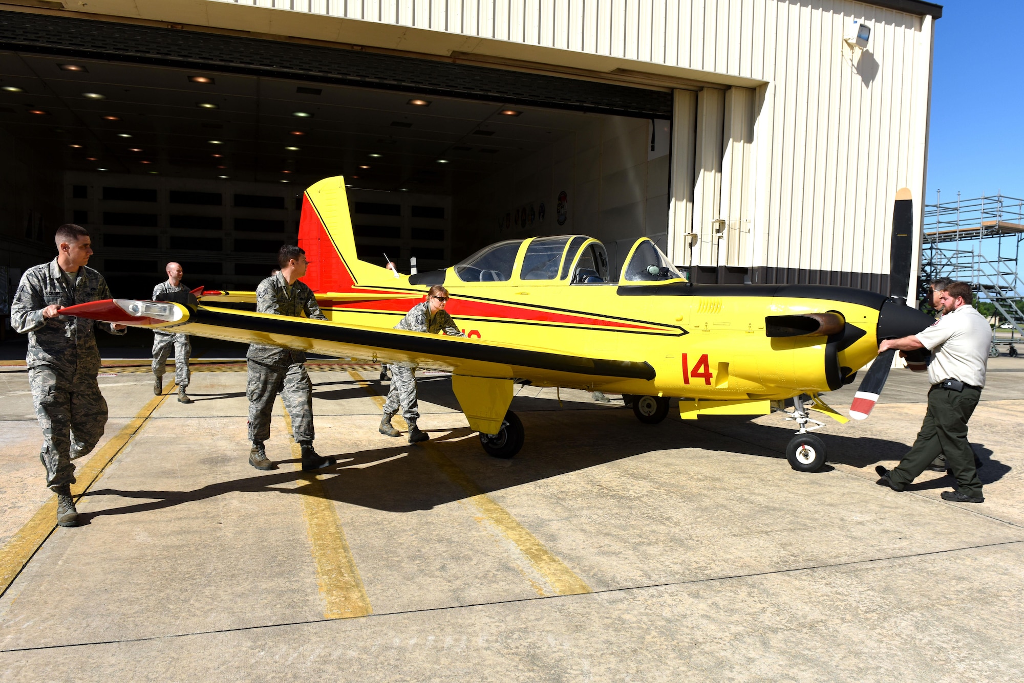 Members from the 4th Equipment Maintenance Squadron corrosion control shop guide a freshly painted North Carolina Forest Service T-34C Turbo Mentor aircraft out of the 4th Equipment Maintenance Squadron corrosion control shop, April 26, 2017, at Seymour Johnson Air Force Base, North Carolina. The aircraft is used as the lead plane to guide tankers over fires so the tankers can drop suppressant on the fire.  (U.S. Air Force photo by Airman 1st Class Ashley Williamson)