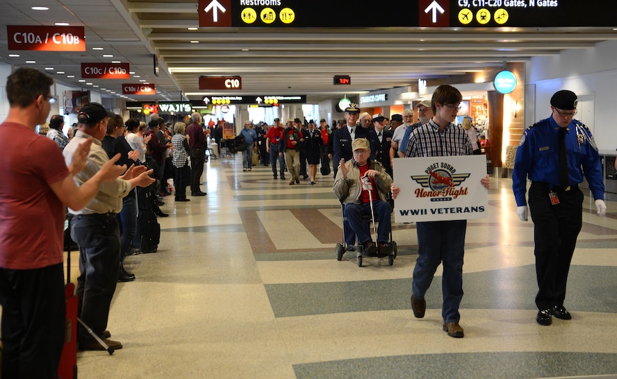 Veterans participating in the Puget Sound Honor Flight are escorted through Seattle-Tacoma International Airport by local service members April 24, 2017, Seattle, Wash. More than 60 service members from Joint Base Lewis-McChord, Wash., and other local duty stations participated in the event to honor the veterans. (U.S. Air Force photo/Senior Airman Jacob Jimenez) 