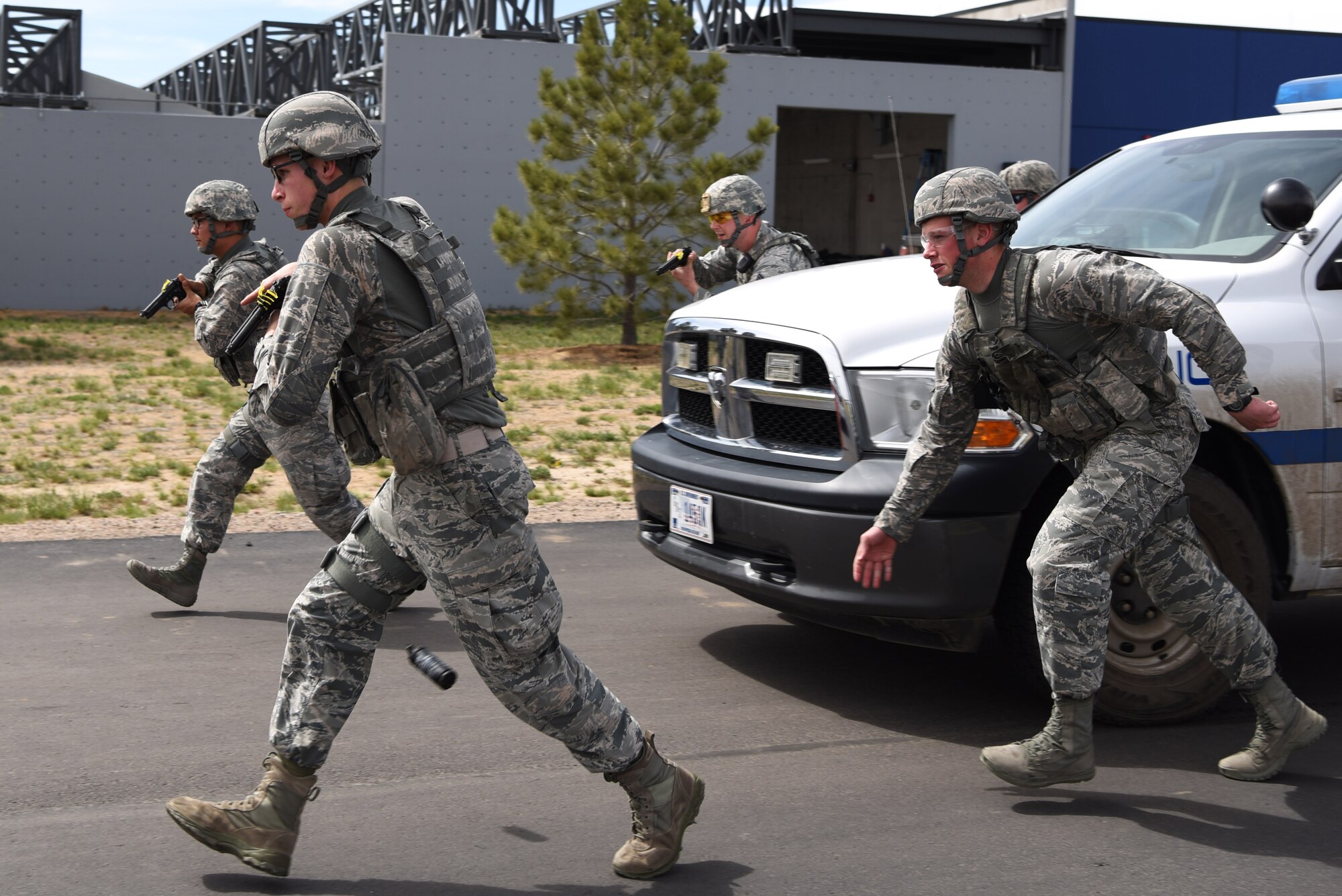 Members of the 460th Security Forces Squadron Emergency Services Team run towards a stopped vehicle prior to apprehending the suspect during a training event Apr. 23, 2017, at the Flatrock Regional Training Center in Commerce City, Colo. Adams County Sheriff Department Special Weapons and Tactics team members worked with the EST to help them learn the process of quickly, safely and effectively approaching a vehicle. (U.S. Air Force photo by Airman 1st Class Holden S. Faul/ Released)