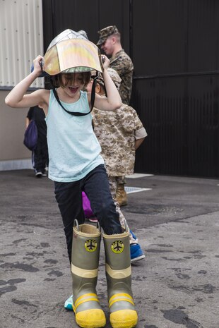 Gwen Baugher, a Junior Recruit Day participant, tries on firefighter boots during the Aircraft Rescue and Firefighter training portion of Marine Aircraft Group 12’s Junior Recruit Day at Marine Corps Air Station Iwakuni, Japan, April 21, 2017. The purpose of Junior Recruit Day is to increase family readiness in the community by showing children and young adults what their parents or guardians do on a daily basis. (U.S. Marine Corps photo by Pfc. Mason Roy)