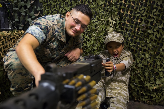 U.S. Marine Corps Cpl. Jeffery Aceti, left, a combat engineer with Marine Wing Support Squadron (MWSS) 171, assists Cosme Rosete, a Junior Recruit Day participant, with the Indoor Simulated Marksmanship Trainer’s M2 .50 caliber heavy-machine gun during Marine Aircraft Group 12’s Junior Recruit Day at Marine Corps Air Station Iwakuni, Japan, April 21, 2017. The purpose of Junior Recruit Day is to increase family readiness in the community by showing children and young adults what their parents do on a daily basis. (U.S. Marine Corps photo by Pfc. Mason Roy)