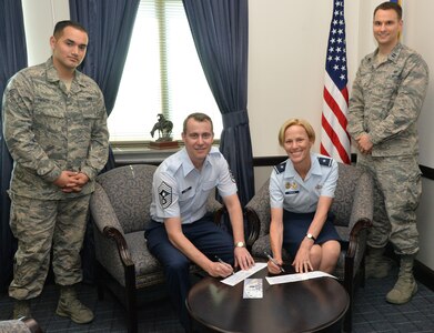 (Left) Senior Airman Luis Tirado-Stoll and (Far Right)  Capt. David  Rolek, chief, 502nd Air Base Wing Magistrate Court and Debarments, 502nd Force Support Group, watch as Chief Master Sgt. Brion Blais, 502nd ABW Command Chief and Brig. Gen. Heather Pringle, 502nd ABW and Joint Base San Antonio commander, sign their Air Force Assistance Fund forms to donate towards a charitable affiliate organization at wing headquarters April 25. The AFAF is an annual effort to raise funds for the charitable affiliates that provide support to Air Force members in need (active duty, retirees, Reservists, Guard and dependents, including surviving spouses). The charitable affiliate organizations provide support in an emergency, with educational needs, or a secure retirement home for widows or widowers of Air Force members in need of financial assistance.  For more information, visit http://www.afassistancefund.org/ or see a squadron key worker any time before May 19 to make a donation.