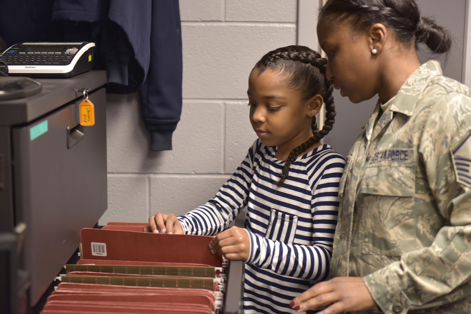 April is designated as the Month of the Military Child, underscoring the important role military children play in the armed forces community. The Month of the Military Child helps raise awareness about the unique struggles military children face, builds resiliency to help them cope with those challenges, and celebrates their sacrifices, which often go unrecognized. Master Sgt. Chastity Morgan, a knowledge operations specialist assigned to the 180th Fighter Wing, and her daughter file personnel mobilization folders at the wing, March 10, 2017 Air National Guard Photo by Tech. Sgt. Nic Kuetemeyer.
