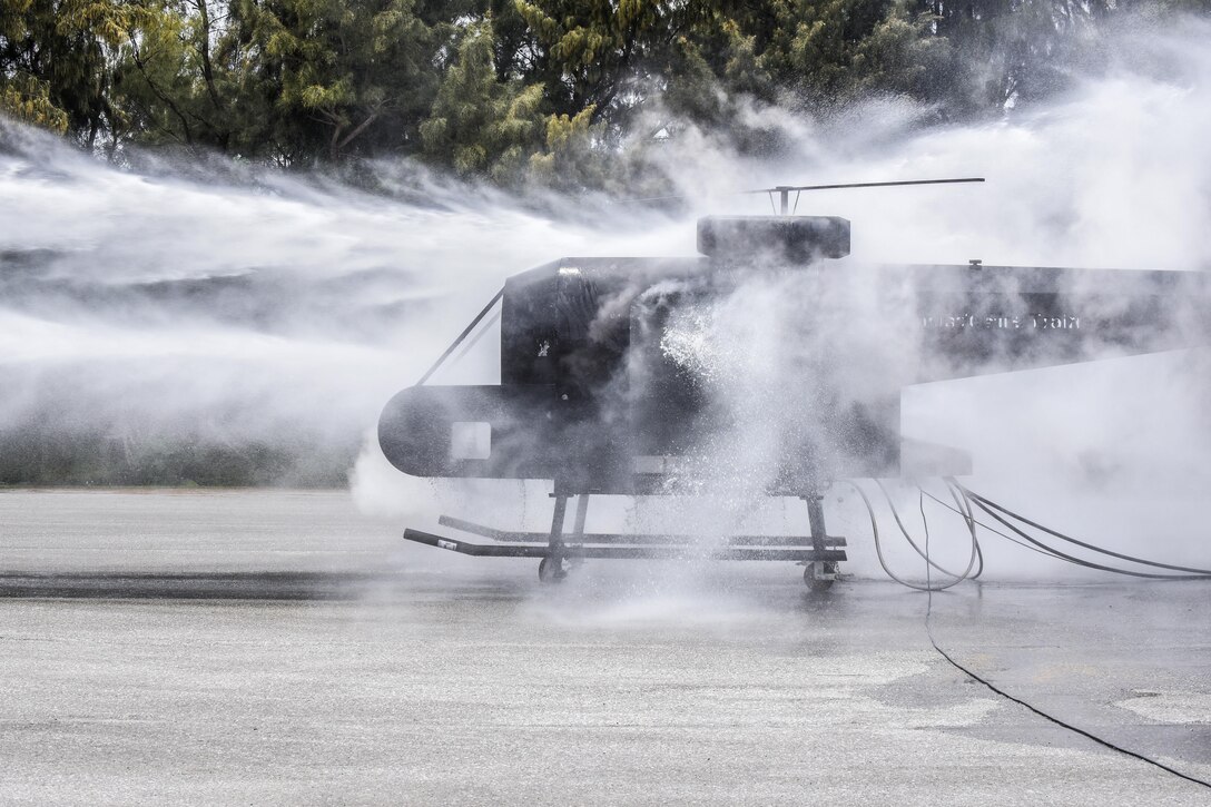 Airmen spray a training helicopter during firefighter training at Kadena Air Base, Japan, April 26, 2017. The airmen are assigned to the 18th Civil Engineer Squadron. Firefighters train on a regular basis to maintain constant readiness for emergencies. Air Force photo by Senior Airman Nick Emerick