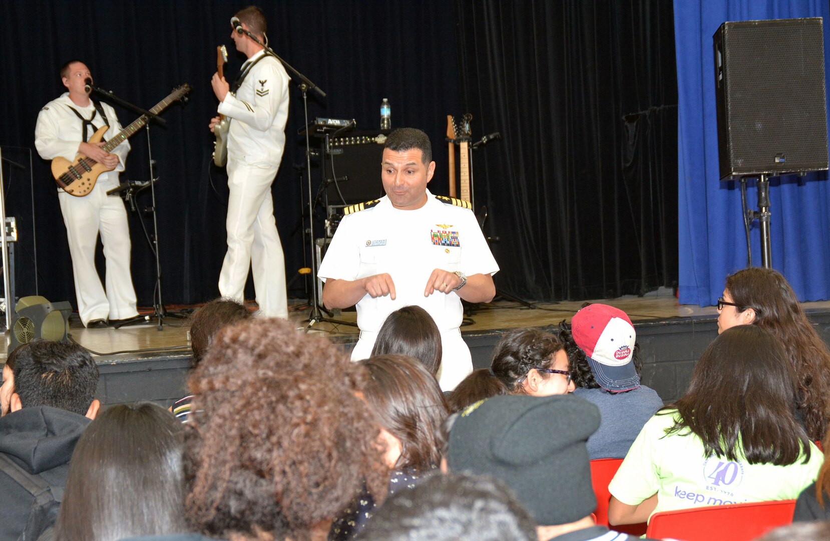 Navy Capt. Edgardo Moreno, executive officer of the USS San Antonio (LPD-17), addresses students at Memorial High School prior to a performance from the “Destroyers,” the popular music group of Navy Band Southwest from San Diego.  Crew members of the USS San Antonio, along with Sailors from Navy Recruiting District San Antonio, visited the school to conduct community outreach and spread Navy Awareness as part of Fiesta festivities.