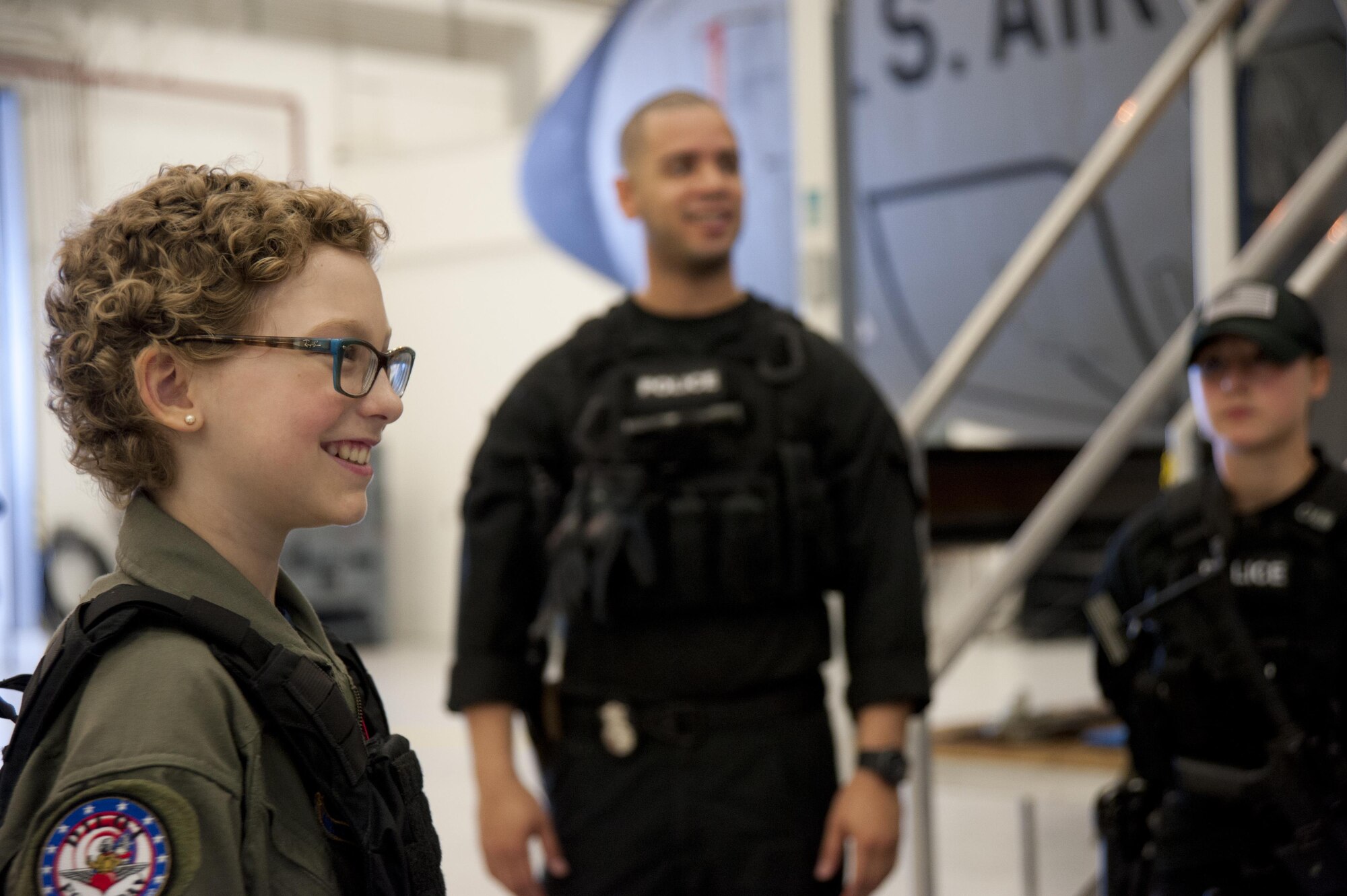Carolyn Shaffer, pilot for a day, smiles as she observes a security forces demonstration April 28, 2017, at Joint Base Andrews, Maryland. Shaffer is diagnosed with Acute Myloid Leukemia and is the 20th pilot for a day. Pilot for a Day is a program which grants children who are diagnosed with cancer the experience of being an aviator for a day. 