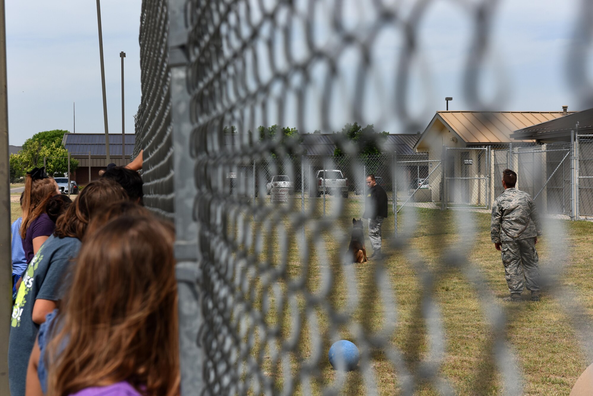 Children peek through a gate at the 17th Security Forces Squadron military dog training on Goodfellow Air Force Base, Texas, April 28, 2017. Various techniques and commands were shown to teach the children the situations security forces cops might experience. (U.S. Air Force photo by Airman 1st Class Caelynn Ferguson/ Released)