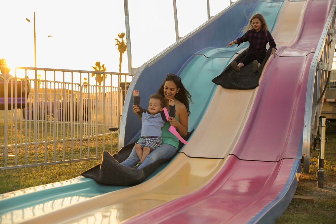 Annie Smack, wife of Gunnery Sgt. Eric Smack, battery gunnery sergeant, 3rd Battalion, 11th Marine Regiment, slides down a giant slide with her son, Carter, 1, during the Earth Day Extravaganza at Lincoln Military Housing Athletic Field aboard Marine Corps Air Ground Combat Center, Twentynine Palms, Calif., April 21, 2017. LMH and Natural Resources and Environmental Affairs hosted the event to make Combat Center patrons more conscious about the environment in a fun and informative way. (U.S. Marine Corps photo by Lance Cpl. Dave Flores)