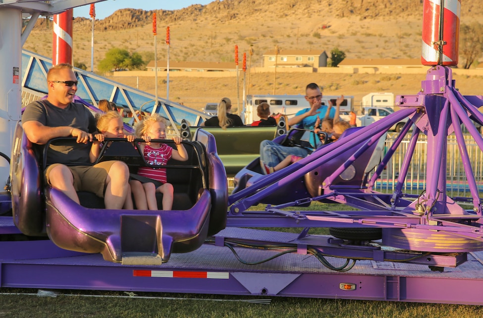 Sgt. Aaron Medlin, squad leader, 3rd Battalion, 4th Marines, 7th Regiment, enjoys a carnival ride with his daughters during the Earth Day Extravaganza at Lincoln Military Housing Athletic Field at Marine Corps Air Ground Combat Center, Twentynine Palms, Calif., April 21, 2017. LMH and Natural Resources and Environmental Affairs hosed the event to encourage Combat Center residents to be more aware of the environment. (U.S. Marine Corps photo by Lance Cpl. Dave Flores)