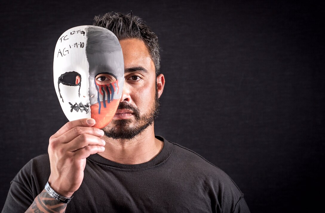 Retired Air Force Tech. Sgt. Chris Ferrell, a former explosive ordnance disposal technician who suffers from post-traumatic stress disorder and traumatic brain injury after combat tours in Afghanistan and Iraq, displays a mask he painted in Hanover, Pa., April 5, 2017. The mask, which bears the initials and dates of death of his teammates, Air Force Tech. Sgts. Tony Campbell and Adam Ginett, is a form of art therapy employed by therapists to help PTSD patients verbalize past traumatic events. It is one of the therapies that will be used at the Air Force's Invisible Wounds clinic scheduled to open at Eglin Air Force Base, Fla., in 2018. Air Force photo by J.M. Eddins Jr.