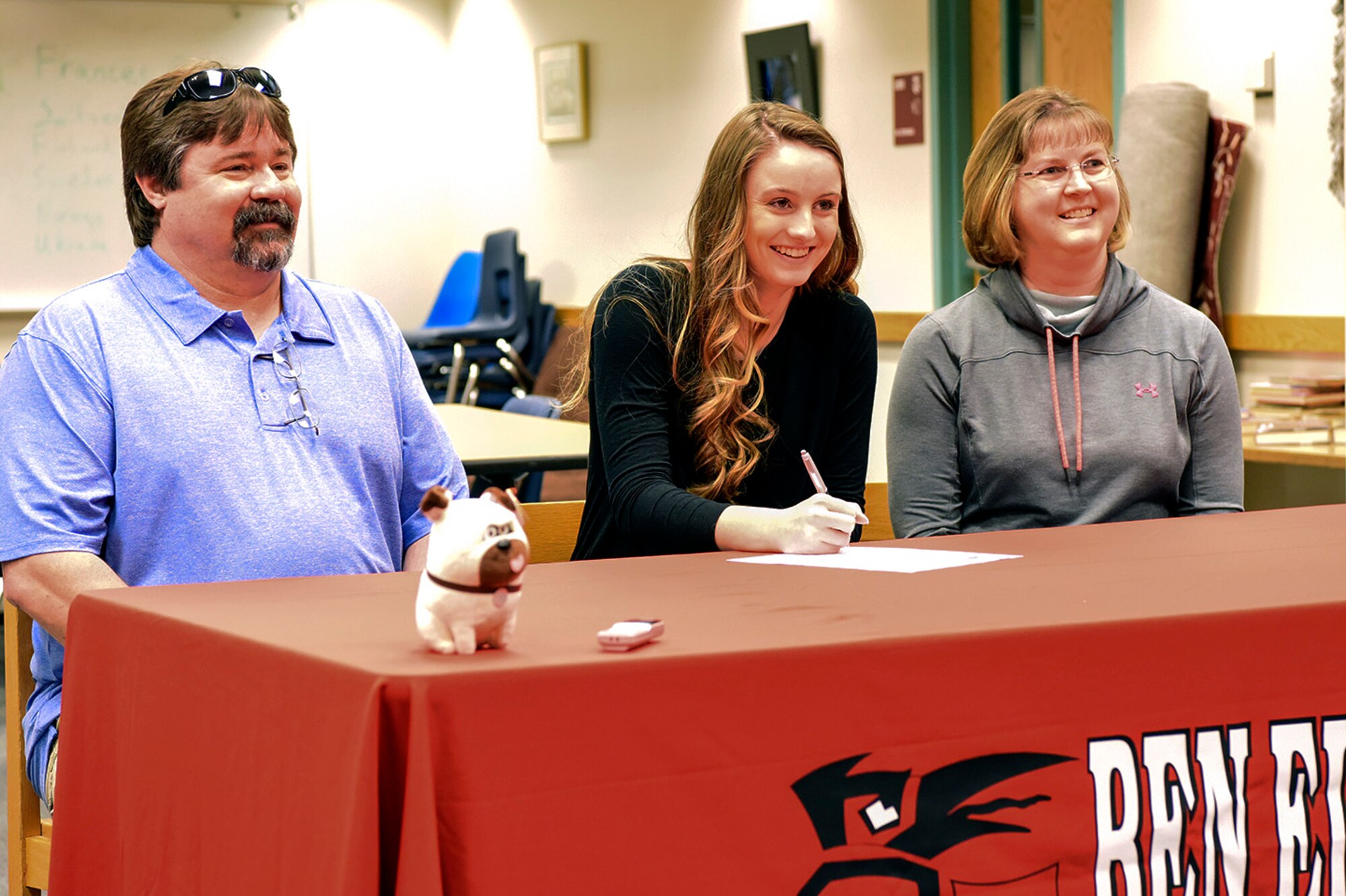 Emily Donovan, daughter of Senior Master Sgt. Rebecca Donovan, 168th Force Development superintendent, Alaska Air National Guard, signs her college letter of intent inside the Ben Eielson High School library, April 27, 2017, Eielson AFB, Alaska. Donovan, sitting between her mom and her dad Mark, will play college volleyball in Tennessee and will study exercise science and sports psychology. (U.S. Air National Guard photo by Senior Master Sgt. Paul Mann/Released)