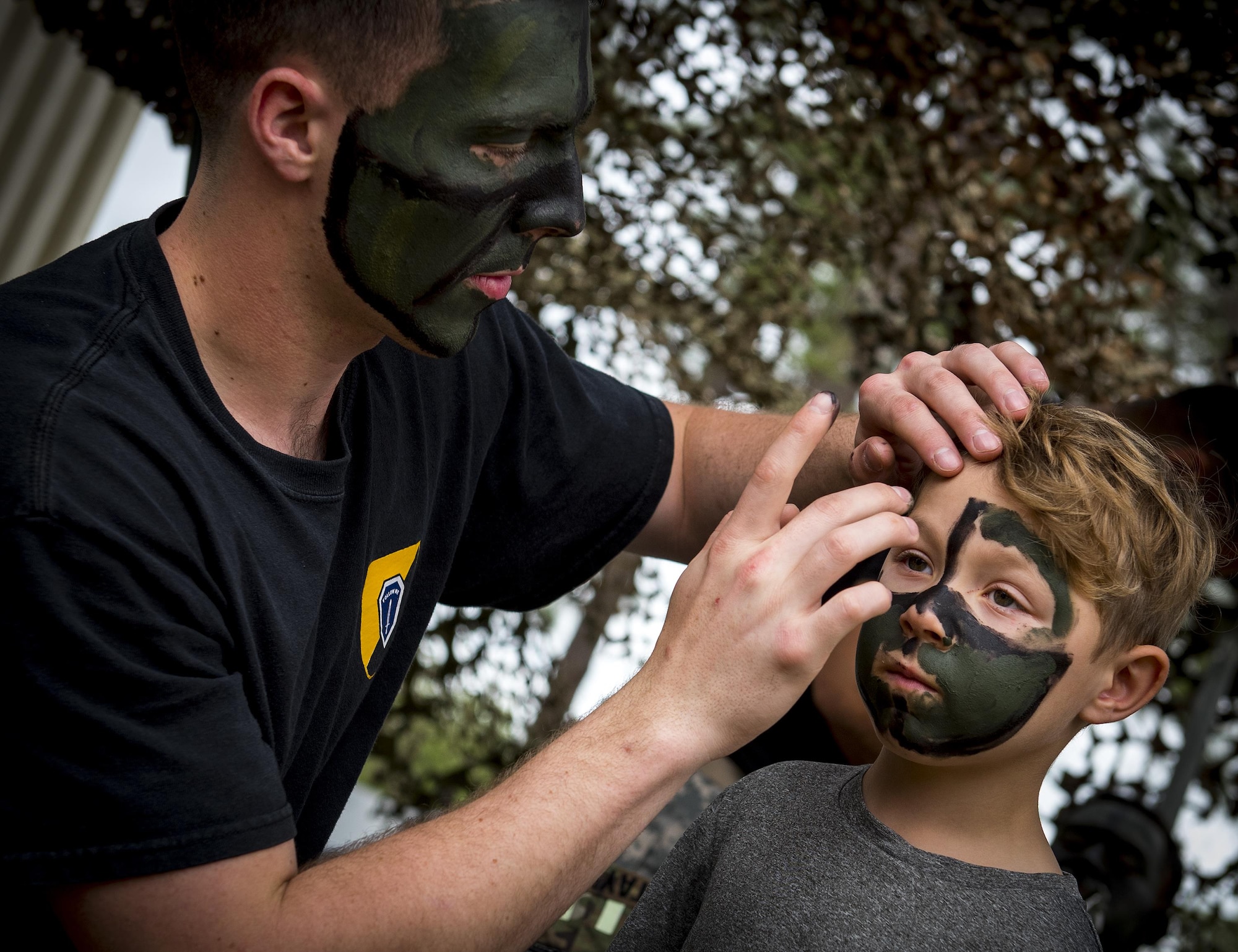 A Soldier applies war paint to a Zeke Zastrow, age 7, during the 6th Ranger Training Battalion’s open house event April 29 at Eglin Air Force Base, Fla. The event was a chance for the public to learn how Rangers train and operate. The event displays showed equipment, weapons, a reptile zoo, face painting and weapon firing among others. The demonstrations showed off hand-to-hand combat, a parachute jump, snake show, and Rangers in action. (U.S. Air Force photo/Samuel King Jr.)