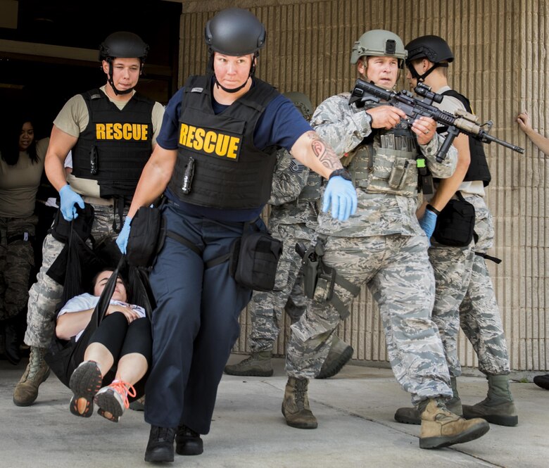 Escorted by 96th Security Forces Squadron Airmen, firefighters carry a simulated wounded victim out of the building during an active shooter exercise at Eglin Air Force Base, Fla., April 11.  The goal of the exercise was to evaluate people’s knowledge and response at the active shooter location and select lockdown locations.  (U.S. Air Force photo/Samuel King Jr.)