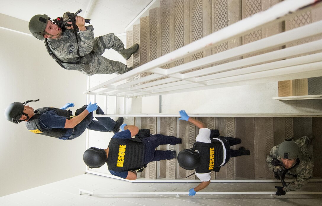 Escorted by 96th Security Forces Squadron Airmen, firefighters make their way up the stairs toward more victims during an active shooter exercise at Eglin Air Force Base, Fla., April 11.  The goal of the exercise was to evaluate people’s knowledge and response at the active shooter location and select lockdown locations.  (U.S. Air Force photo/Samuel King Jr.)