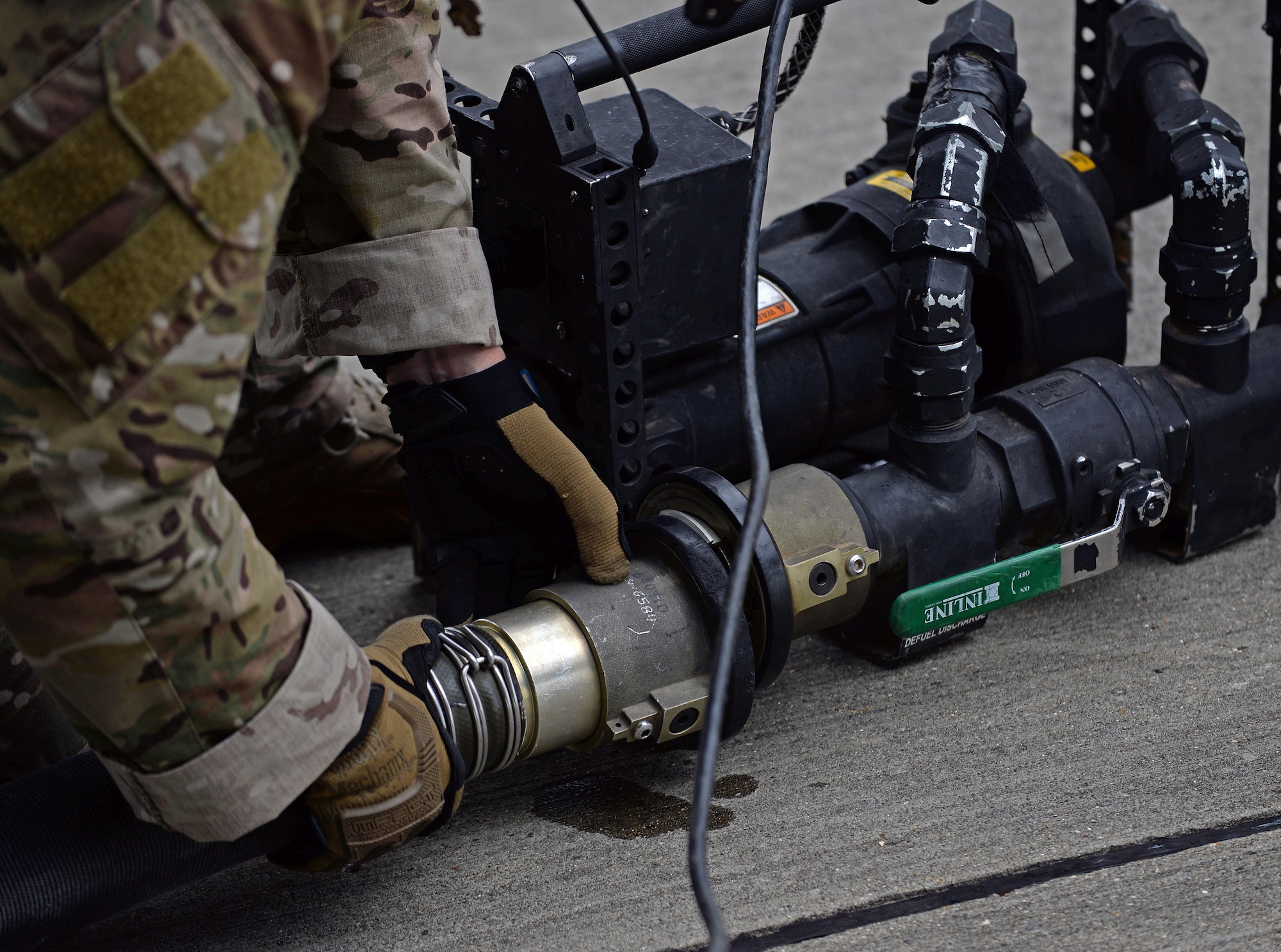 A U.S. Air Force 67th Special Operations Squadron loadmaster hooks up a fuel hose running from an MC-130J Commando II to a pump July 26, 2017, on RAF Mildenhall, England. The pump is used to assist with pumping any residual fuel from the hose back into the MC-130J. (U.S. Air Force photo by Airman 1st Class Luke Milano)