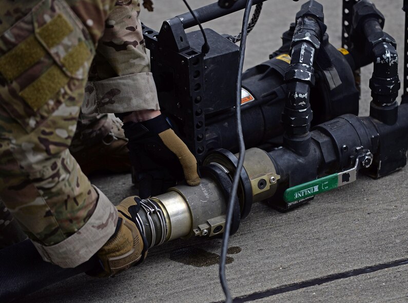 A U.S. Air Force 67th Special Operations Squadron loadmaster hooks up a fuel hose running from an MC-130J Commando II to a pump July 26, 2017, on RAF Mildenhall, England. The pump is used to assist with pumping any residual fuel from the hose back into the MC-130J. (U.S. Air Force photo by Airman 1st Class Luke Milano)