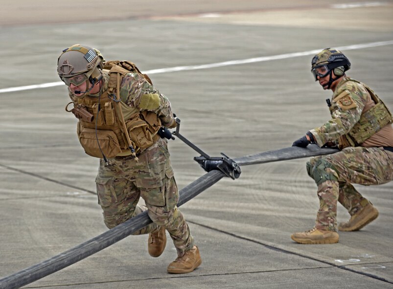 U.S. Air Force Airman 1st Class Michael Ricci, right, 100th Logistics Readiness Squadron Forward Arming and Refueling Point  technician aids a U.S. Air Force 67th Special Operations Squadron loadmaster with removing residual fuel from a hose using a tool called a ‘squeegee’ July 26, 2017, on RAF Mildenhall, England. During the Forward Arming and Refueling Point exercise, approximately 27,000 pounds of fuel was transferred from an MC-130J to four F-15Cs. (U.S. Air Force photo by Airman 1st Class Luke Milano)