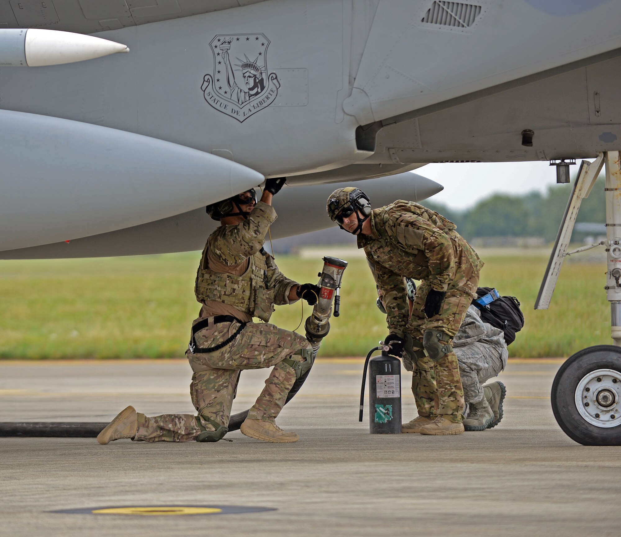 U.S. Air Force Airman 1st Class Michael Ricci, 100th Logistics Readiness Squadron Forward Arming and Refueling Point, or FARP, technician begins to hook up a fuel hose to a F-15C Eagle from RAF Lakenheath as U.S. Air Force Staff Sgt. Brian Nichols, 100th LRS FARP technician stands nearby with a fire extinguisher during a FARP exercise July 26, 2017, on RAF Mildenhall, England. The FARP exercise brought together the 352d Special Operations Wing, 48th Fighter Wing and 100th Air Refueling Wing. (U.S. Air Force photo by Airman 1st Class Luke Milano)