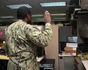 Army Maj. Leon H. Matthias Jr., assigned to 532nd Military Intelligence Battalion, 501st Military Intelligence Brigade in Camp Humphreys, South Korea, on screen, administers the oath of enlistment to his brother Information Systems Technician 2nd Class Lucian Matthias, assigned to U.S. Naval Forces Central Command, via a video teleconference. (U.S. Navy photo by Mass Communication Specialist 2nd Class Victoria Kinney)