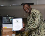 MANAMA, Bahrain (July 27, 2017) Information Systems Technician 2nd Class Lucian Matthias, assigned to U.S. Naval Forces Central Command, poses for a photo after having been administered the oath of enlistment by his brother Army Maj. Leon H. Matthias Jr., assigned to 532nd Military Intelligence Battalion, 501st Military Intelligence Brigade in Camp Humphreys, South Korea, on screen, via a video teleconference. (U.S. Navy photo by Mass Communication Specialist 2nd Class Victoria Kinney)