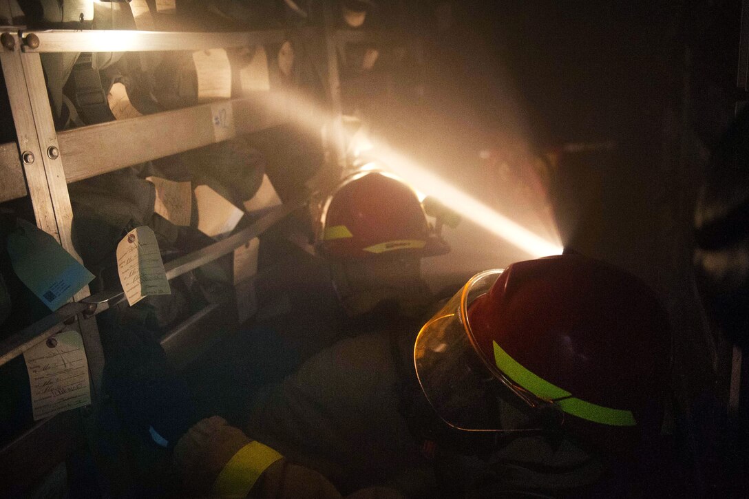Sailors investigate a smoke-filled space during a simulated general quarters drill aboard the amphibious assault ship USS America in the Pacific Ocean, July 24, 2017. Navy photo by Petty Officer 2nd Class Alexander A. Ventura II