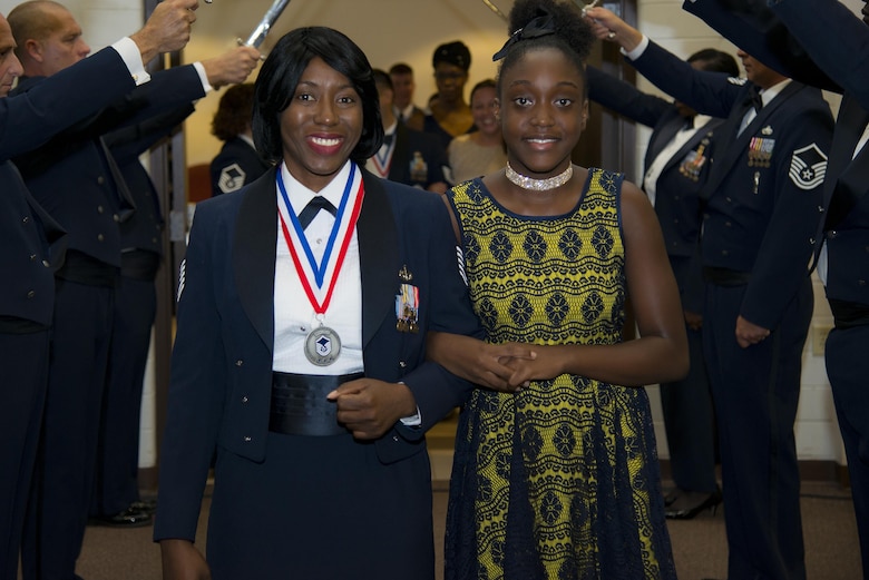 Tech. Sgt. Michaela Maximin, 23d Force Support Squadron chief of readiness and plans, and her daughter Naiya, walk past a saber arch during a Senior NCO induction ceremony, July 28, 2017, at Moody Air Force Base, Ga. The event honored and celebrated the Airmen who have earned the rank of master sergeant. (U.S. Air Force photo by Airman 1st Class Erick Requadt)