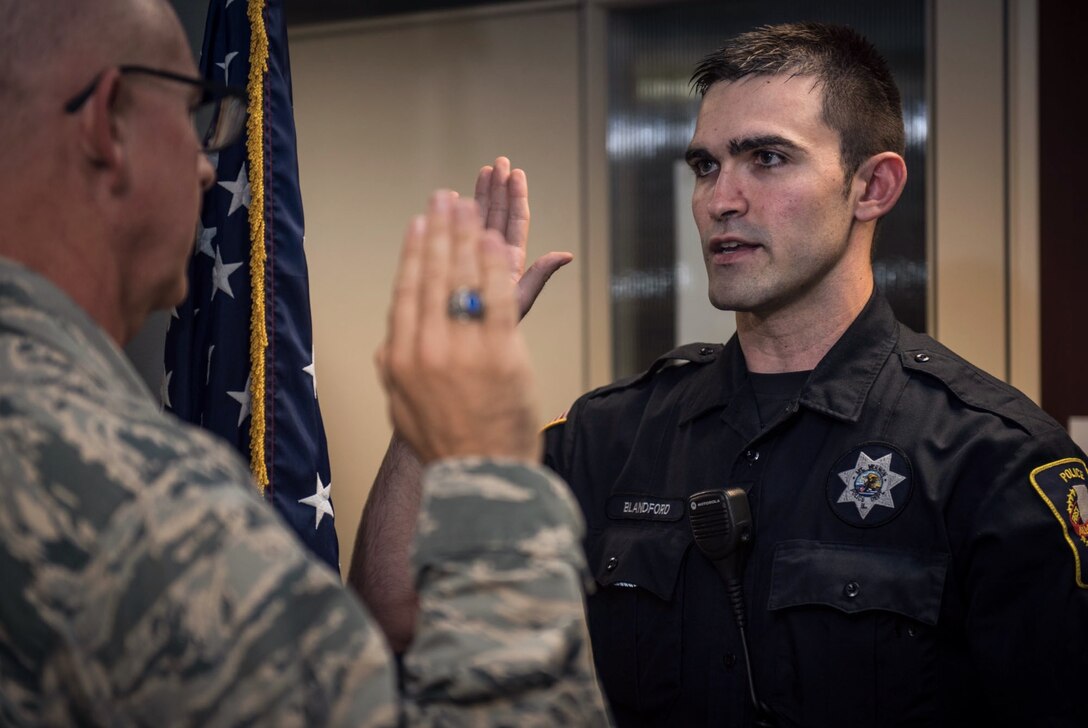 Holding the "blue line" steady in two places is the next challenge for an enlistee who contacted the wing.  Here, Chief of Public Affairs, Lt. Col Stan Paregien, performs the oath of enlistment for the newest Airman joining the 932nd Airlift Wing on July 31, 2017, at Scott Air Force Base, Illinois.  Andrew Blandford is a police officer in Illinois, who became interested in the explosive ordnance disposal speciality within the Air Force Reserve, after talking to his childhood friend, Airman 1st. Class Mathew Brummel, who works with the 932nd Airlift Wing's Operations Group.  They have been friends since kindergarten and Brummel recently spoke about his family connections and motivation to join the reserve and the importance of staying close to family while serving.  Blandford's line recruiter is Tech. Sgt. Brittany Paus.  To help others interested in joining the 932nd Airlift Wing, the toll free number is 1-800-257-1212, for more information.  (U.S. Air Force photo by Christopher Parr)
