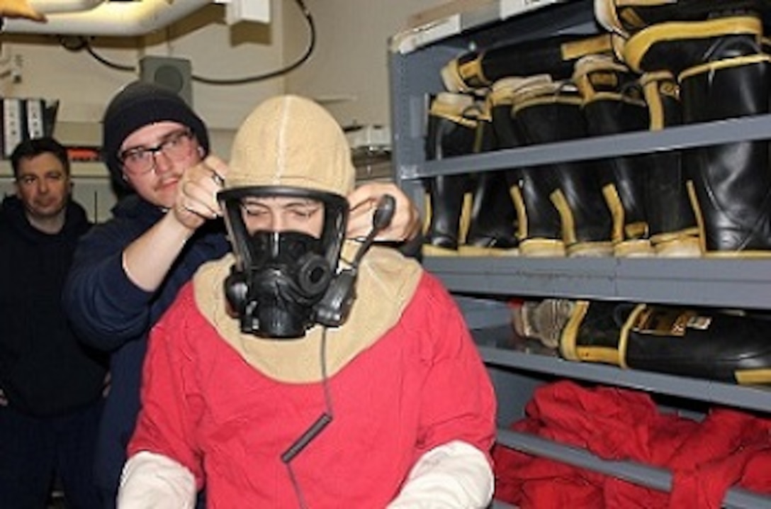 SN Weesner assists SA Rife in donning an SCBA mask.