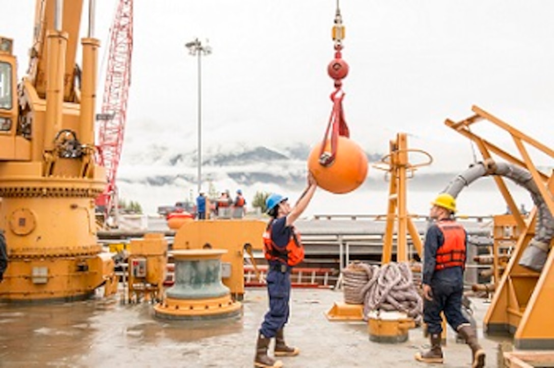 SN Matt Weesner and BM3 Ben Ahlin guide a buoy onto the working deck.