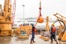 SN Matt Weesner and BM3 Ben Ahlin guide a buoy onto the working deck.