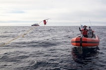 A crewmember prepares to catch a heaving line for towing operations.