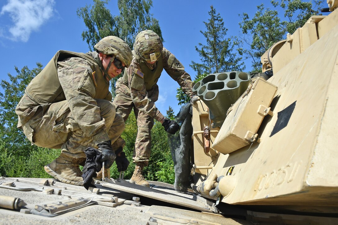 Soldiers perform maintenance on a tank.