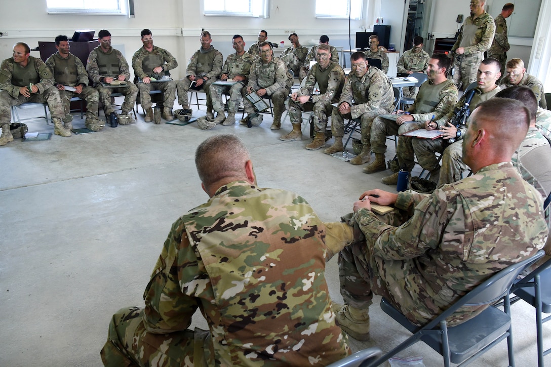 Soldiers sit to discuss a live-fire exercise.