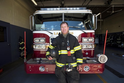 Tom Farrington, a firefighter with the Indianapolis Fire Department and a member of the Indiana Army National Guard, stands in front of one of the department’s ladder trucks. Farrington said the skills he uses as a firefighter easily translate over to the military side, just as his military skills benefit him as a firefighter.