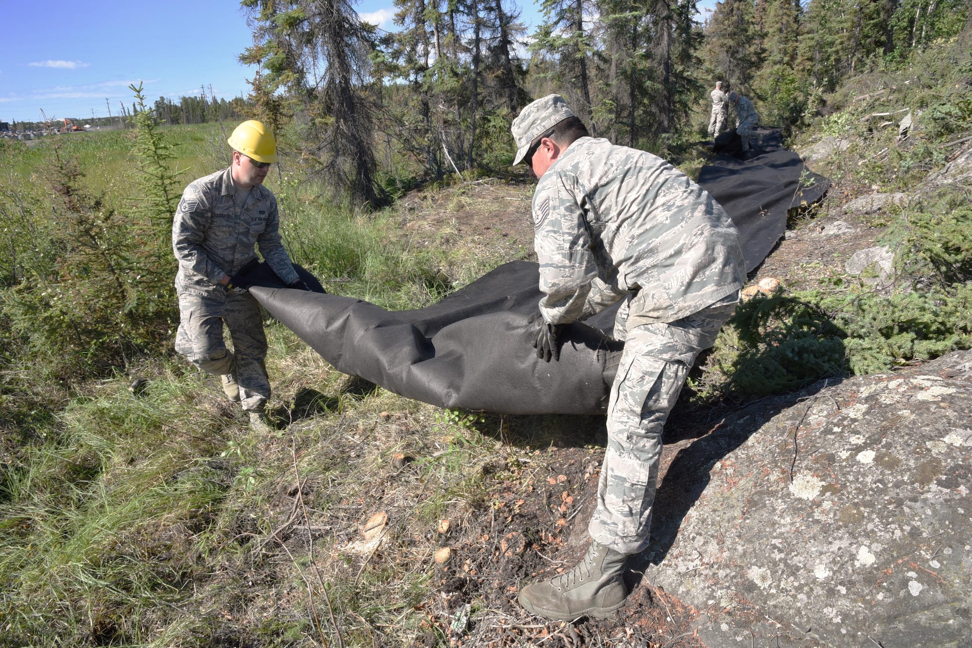 Oregon Air National Guard Staff Sgt. Daniel Hagemier, assigned to the 142nd Fighter Wing Civil Engineers Squadron (left), and Tech. Sgt. Charles Jedda (right), move a large role of stabling material to provide a base for rock and other materials, extending a public trail at Niven Lake at Yellowknife, Northwest Territories, Canada, July 18, 2017. The Civil Engineer Airmen are spending two-weeks in Canada working with Canadian Armed Forces members from Cold Lake, Alberta, Canada, on a variety of projects during their Deployment for Training (DFT). (U.S. Air National Guard photo/Master Sgt. John Hughel, 142nd Fighter Wing Public Affairs)