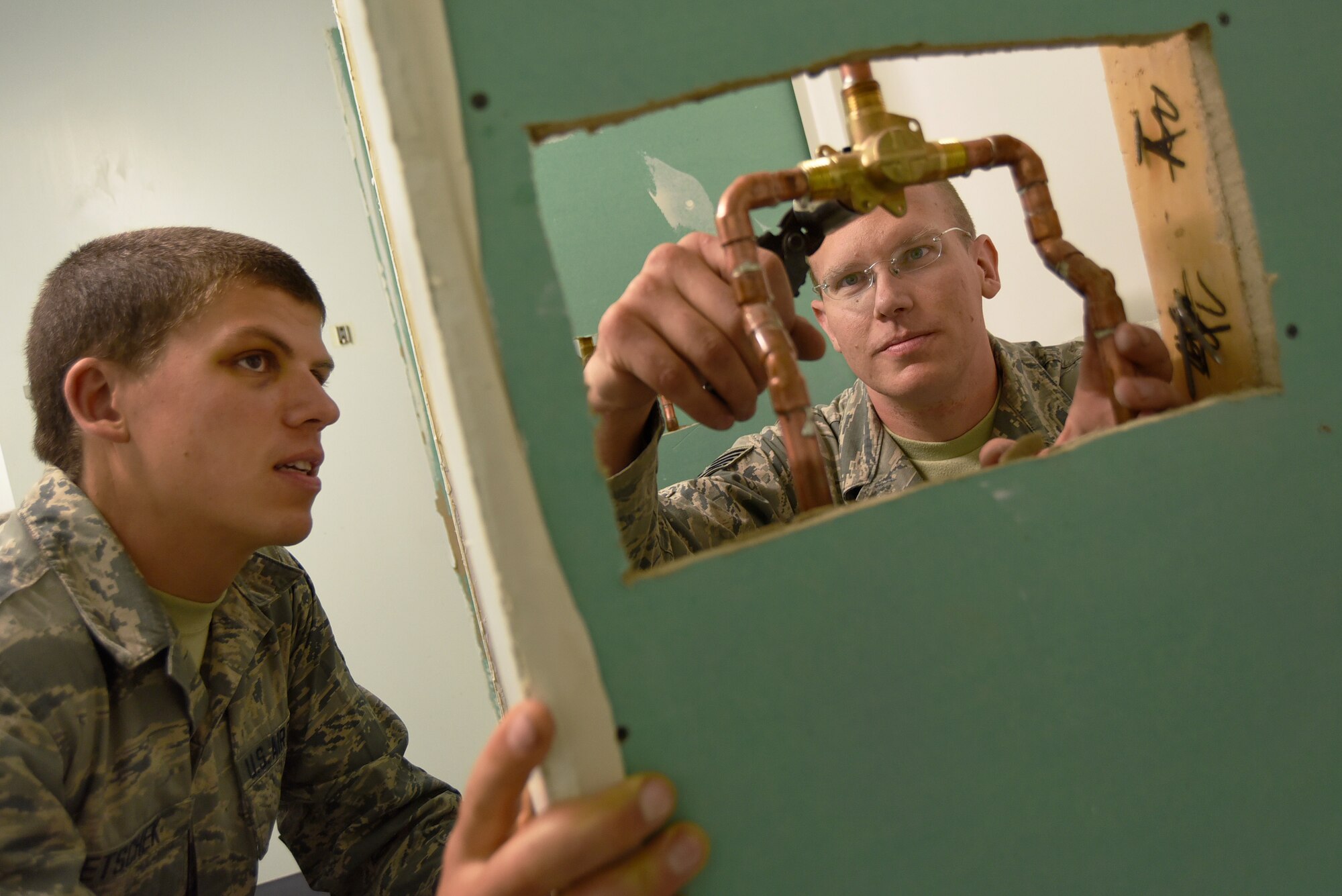 Oregon Air National Guard Staff Sgt. Benjamin Schultz (right), makes adjustments to newly installed plumbing fixtures, while Airman 1st Class Joshua Bietschek (left), observes the procedures as part of his ongoing training, as the two members assigned to the 142nd Civil Engineer Squadron work on a variety of construction and repair projects during their Deployment For Training (DFT) in Yellowknife, Northwest Territories, Canada, July 21, 2017. The Oregon Airmen are also collaborating with Canadian Armed Forces members from Cold Lake, Alberta, who are also deployed to Yellowknife for training. (U.S. Air National Guard photo/Master Sgt. John Hughel, 142nd Fighter Wing Public Affairs)
