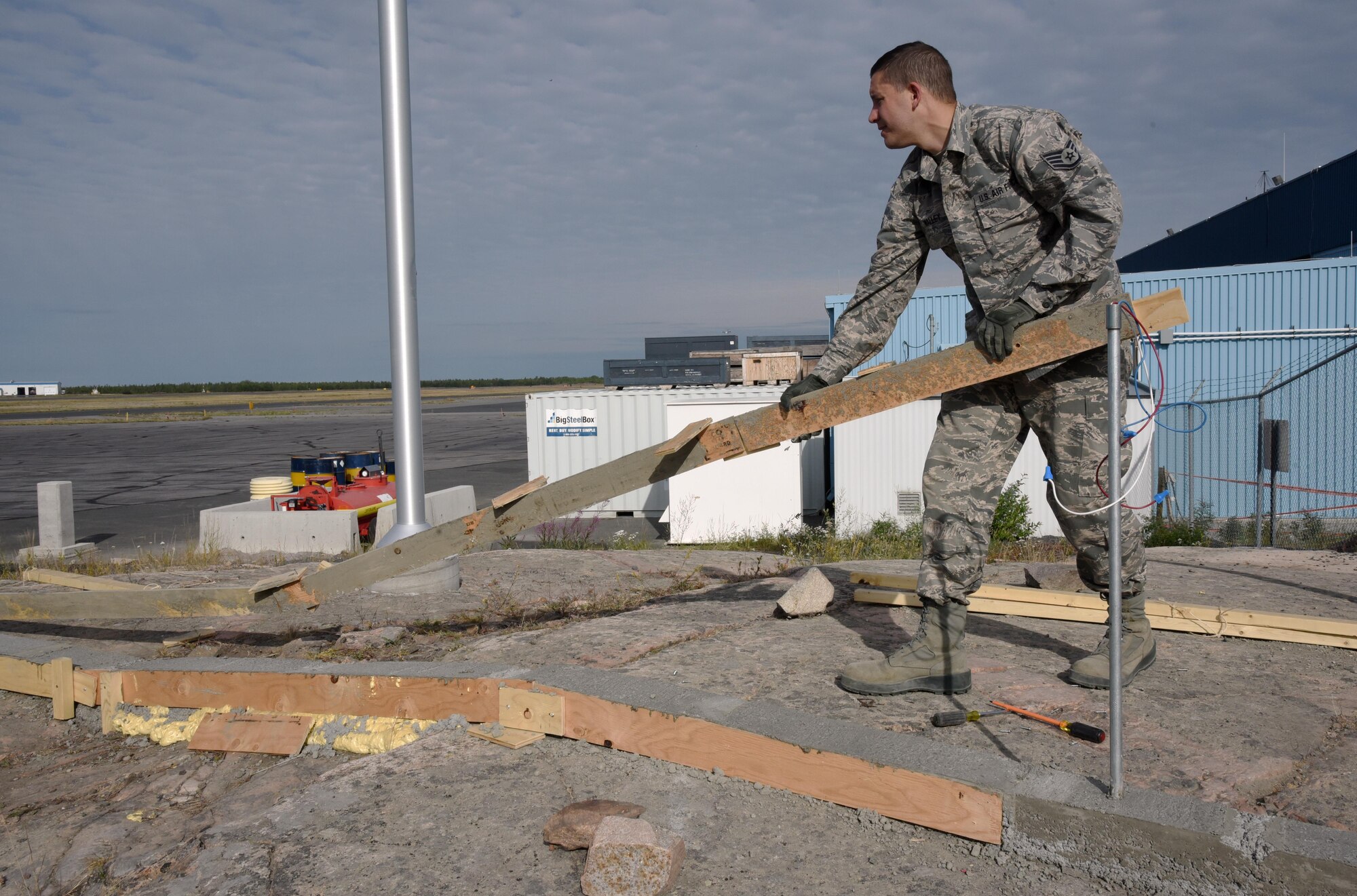 Oregon Air National Guard Staff Sgt. Christopher Walley, assigned to the 142nd Fighter Wing Civil Engineer Squadron (CES) removes wooden concrete forms as part of a lighting project at the 440th Squadron/Escadrille, Yellowknife, Northwest Territories, Canada, July 24, 2017. (U.S. Air National Guard photo/Master Sgt. John Hughel, 142nd Fighter Wing Public Affairs)