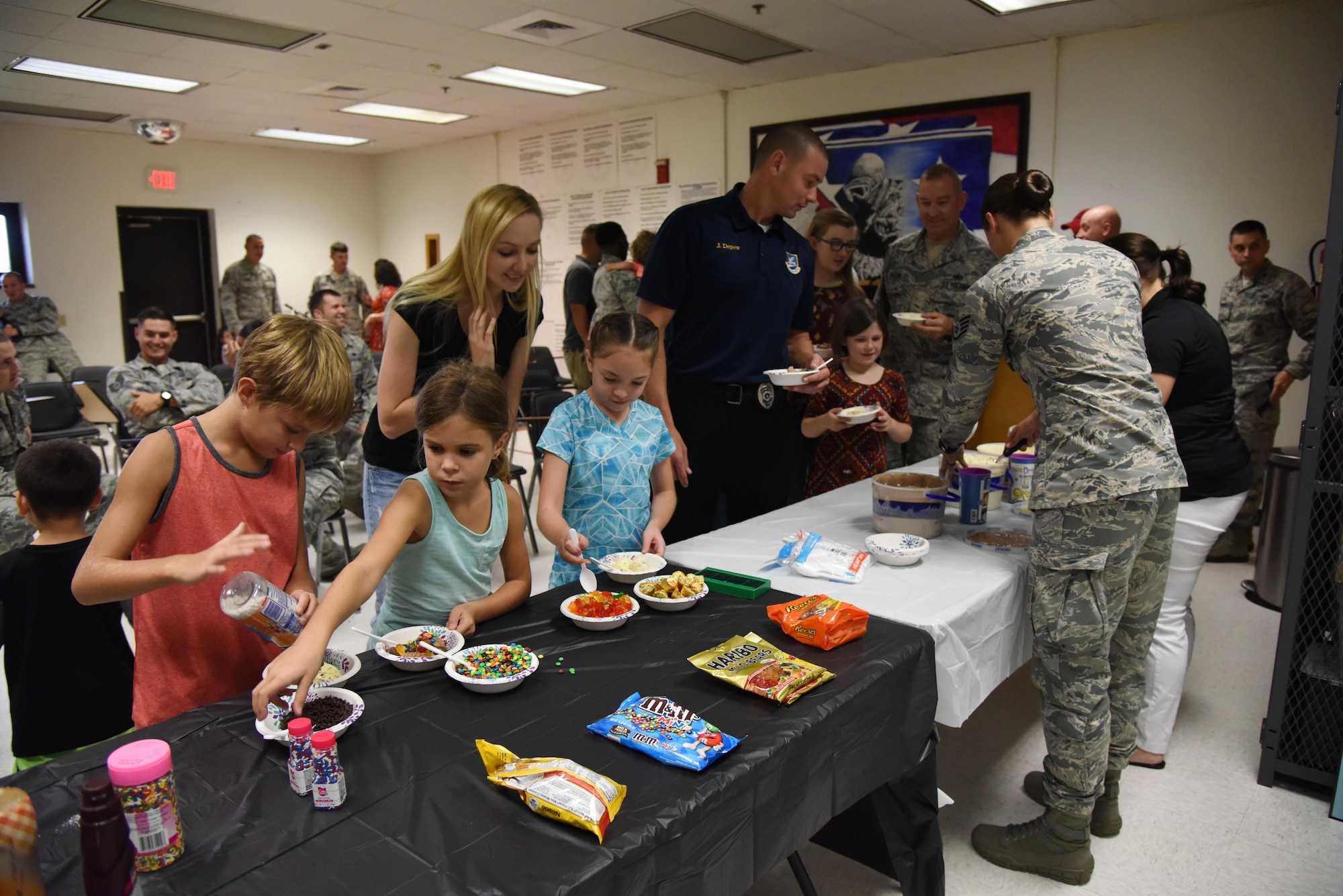 Personnel and family members from the 81st Security Forces Squadron make a bowl of ice cream during a family ice cream social at the 81st SFS building July 27, 2017, on Keesler Air Force Base, Miss. The event, hosted by the 81st SFS Defenders Council and Key Spouses, also consisted of a military working dog demonstration and a combat arms weapons display. (U.S. Air Force photo by Kemberly Groue)