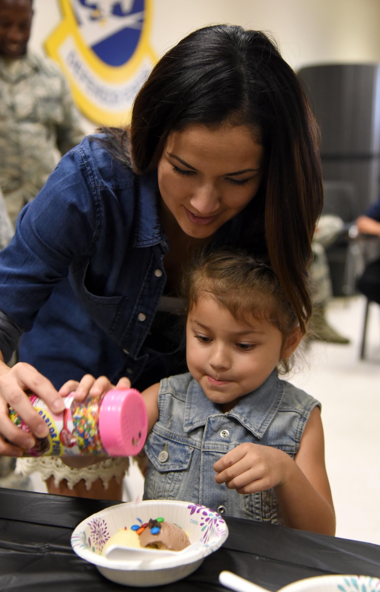 Priscilla and Rosalie Murray, family members of Maj. Jonathon Murray, 81st Security Forces Squadron commander, sprinkle candy on their ice cream during a family ice cream social at the 81st SFS building July 27, 2017, on Keesler Air Force Base, Miss. The event, hosted by the 81st SFS Defenders Council and Key Spouses, also consisted of a military working dog demonstration and a combat arms weapons display. (U.S. Air Force photo by Kemberly Groue)