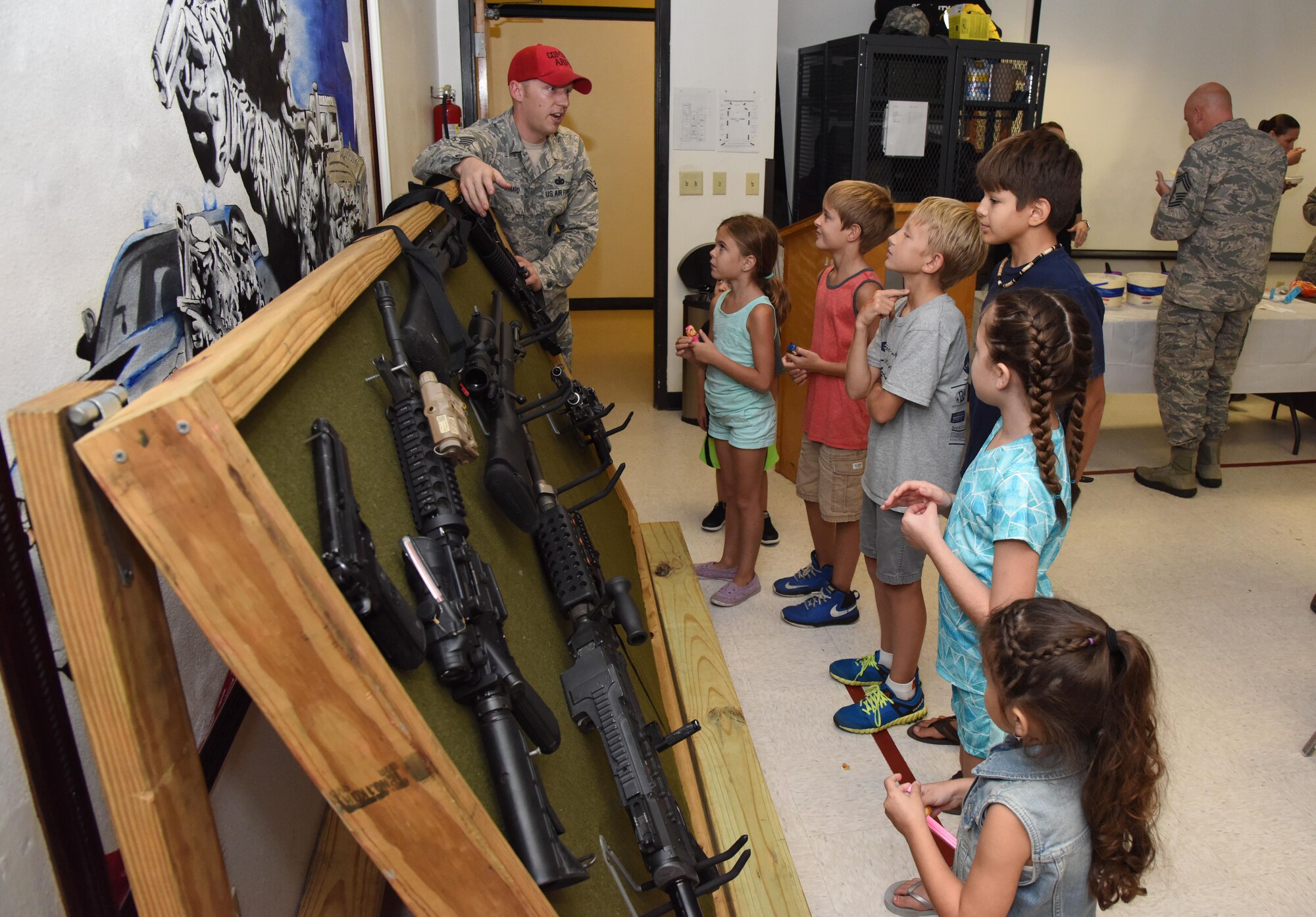 Staff Sgt. Jarrod Kinard, 81st Security Forces Squadron combat arms NCO in charge, briefs family members about weapons safety during a family ice cream social at the 81st SFS building July 27, 2017, on Keesler Air Force Base, Miss. The event, hosted by the 81st SFS Defenders Council and Key Spouses, also consisted of a military working dog demonstration and ice cream. (U.S. Air Force photo by Kemberly Groue)