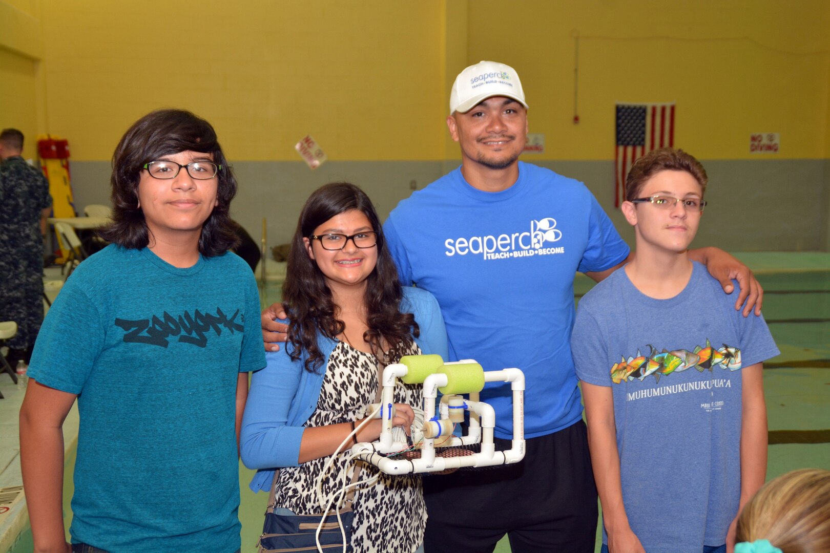 John Munoz, a computer science teacher with Alamo Heights High School and Summer SeaPerch instructor for Northeast Lakeview College, stands with one of the six teams he coached during a SeaPerch scrimmage held at the Eastside Branch Boys & Girls Club July 27. The event was held on the final day of the SeaPerch Regional Challenge Prep Camp hosted by Northeast Lakeview College and the Boys & Girls Clubs of San Antonio, in cooperation with Navy City Outreach Southwest Region and Navy Recruiting District (NRD) San Antonio. The scrimmage consisted of the Speed Obstacle and Challenge Courses. 