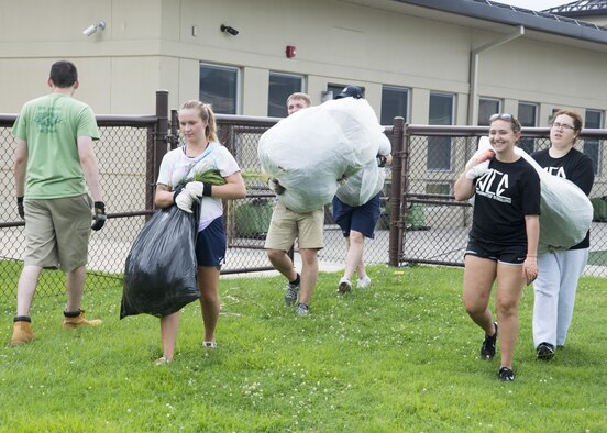 Airmen with the Airmen Committed to Excellence council carries bags of grass after landscaping July 27, 2017, at the Child Development Center on Dover Air Force Base, Del. The council cleared a small section of the playground of weeds to let the CDC revamp the area. (U.S. Air Force photo by Staff Sgt. Jared Duhon)