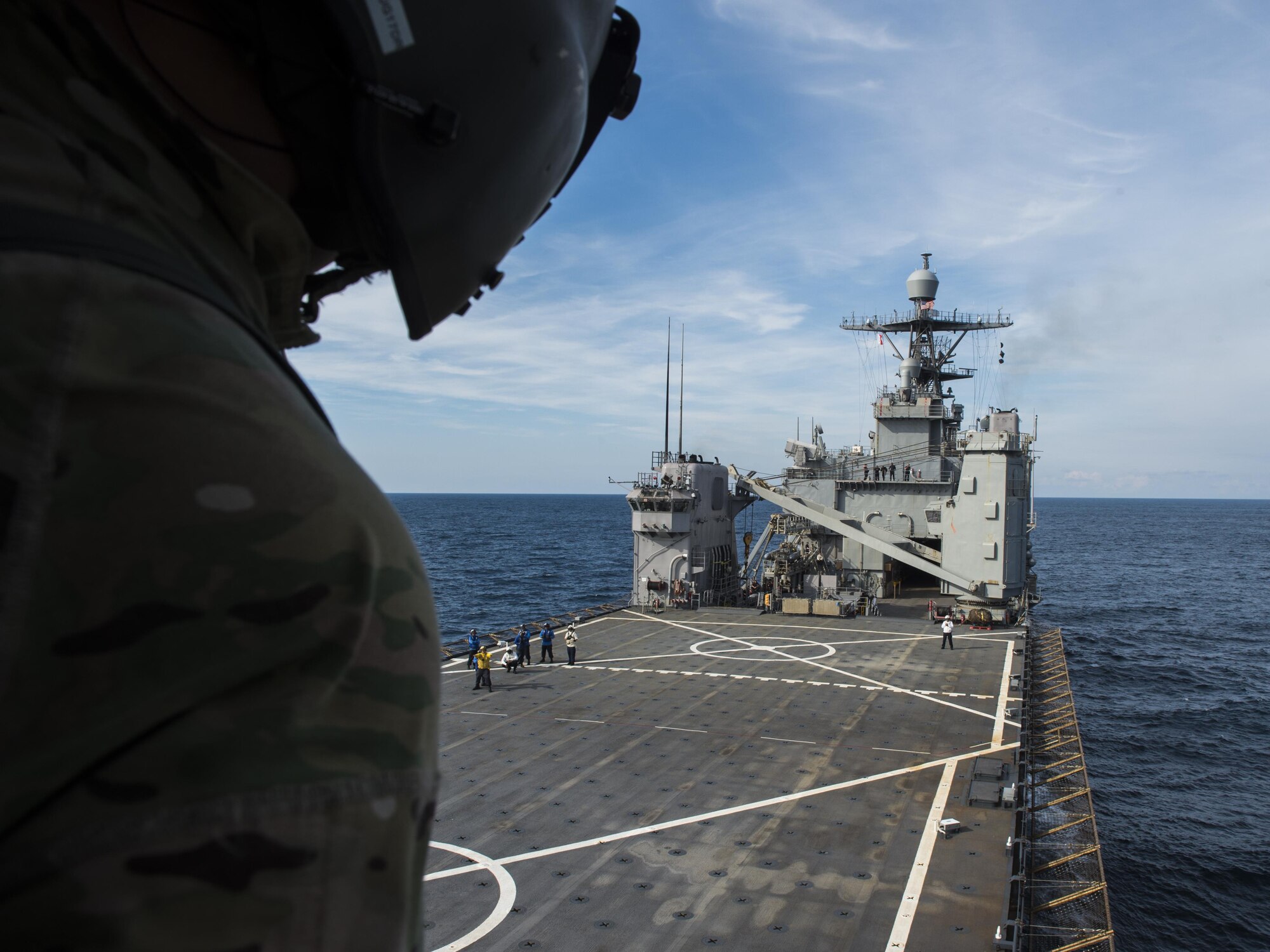 A flight engineer with the 8th Special Operations Squadron watches as his CV-22 Osprey tiltrotor aircraft approaches the amphibious dock landing ship USS Oak Hill (LSD 51) during a deck landing qualification flight off the coast of Virginia, July 25, 2017. Flight engineers are responsible for watching the approach and relaying the approximate distance between his aircraft and the carrier to the pilots, ensuring a safe landing. (U.S. Air Force photo by Airman 1st Class Joseph Pick)