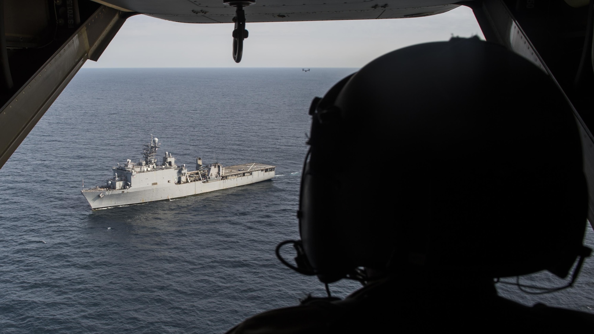 A flight engineer with the 8th Special Operations Squadron looks on as a CV-22 Osprey tiltrotor aircraft departs the amphibious dock landing ship USS Oak Hill (LSD 51) during a deck landing qualification flight off the coast of Virginia, July 25, 2017. Deck landing capabilities allow 8th SOS aircrew to expand the Osprey’s global reach. (U.S. Air Force photo by Airman 1st Class Joseph Pick)