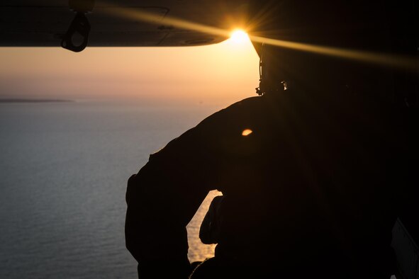 A flight engineer with the 8th Special Operations Squadron scans the horizon during a training mission off the coast of Virginia, July 26, 2017. Flight engineers are responsible for watching the approach and relaying the approximate distance between his aircraft and the carrier to the pilots, ensuring a safe landing. (U.S. Air Force photo by Airman 1st Class Joseph Pick)