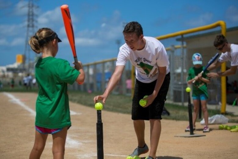 Lance Cpl. Danielle Prentice coaches a girl on how to hold her bat at a youth baseball clinic
