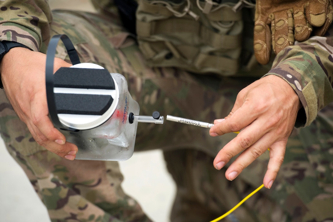 A service member holds an explosive charge in his hands.