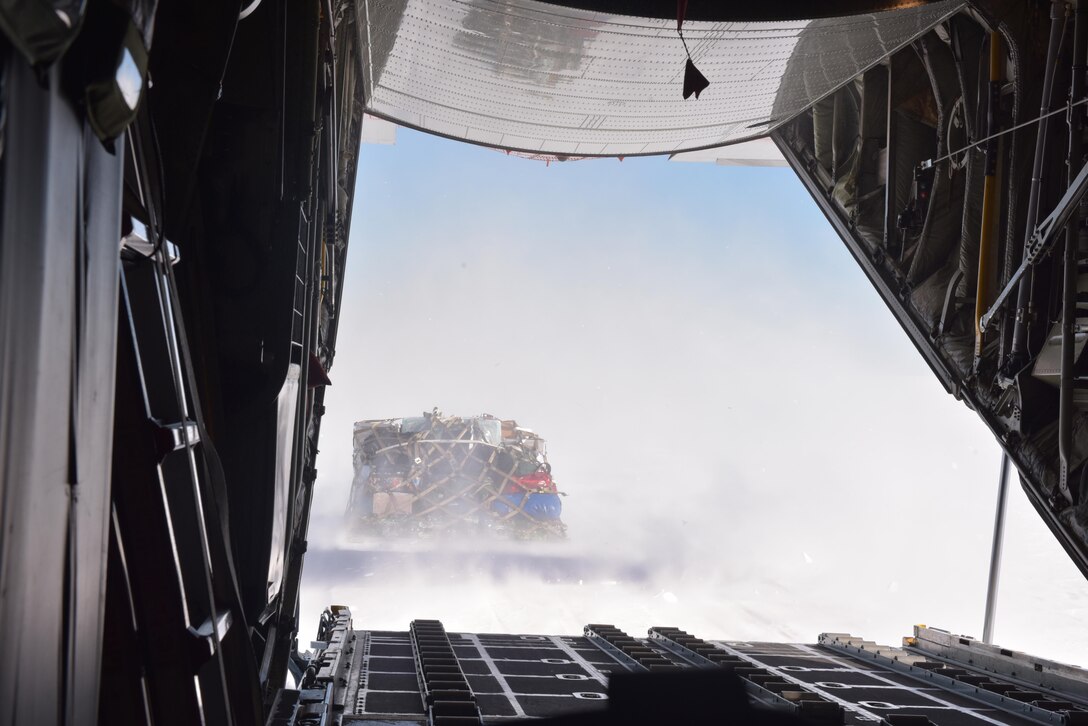 A cargo pallet lands in the snow behind an LC-130 Hercules "Skibird" as New York Air National Guardsmen assigned to the 109th Airlift Wing deliver supplies to scientists at the East Greenland Ice Core Project, July 29, 2017.